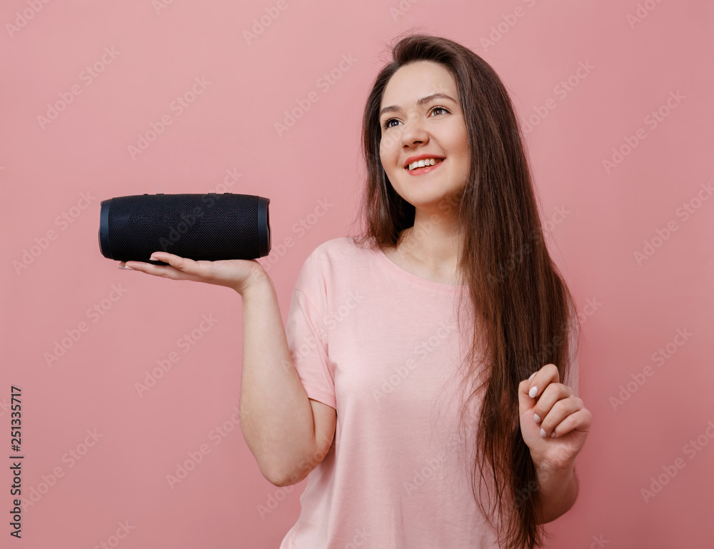 young woman with a portable loudspeaker in hand on pink background young woman with a portable loudspeaker in hand on pink background