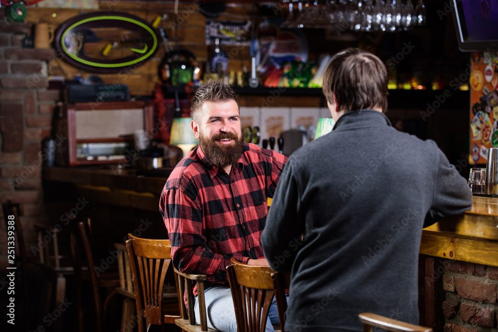 Weekend leisure. Friday relaxation in pub. Friends relaxing in pub. Friendly conversation with stranger. Hipster brutal bearded man spend leisure with friend bar counter in pub. Men relaxing in pub