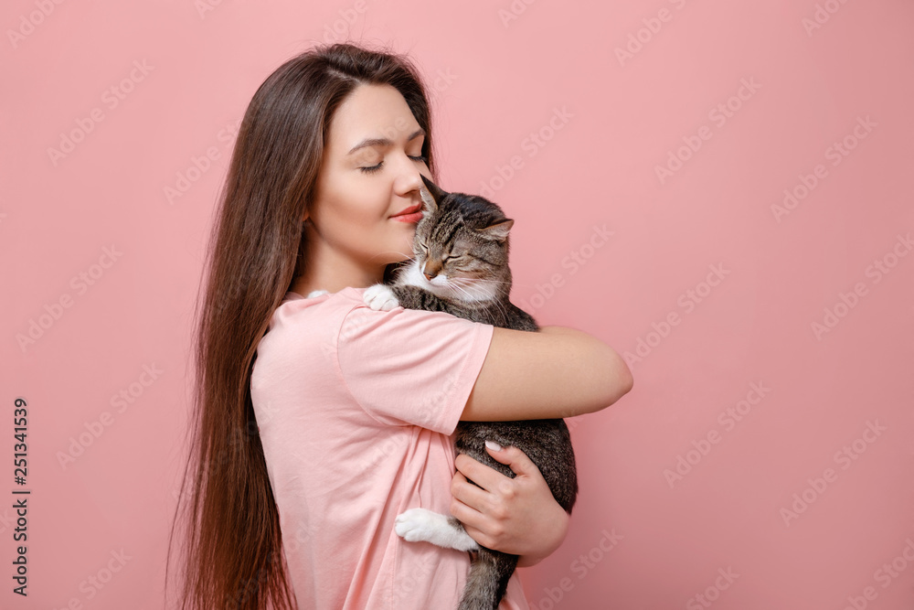 young attractive woman hugging cat in hands, pink background young attractive woman hugging cat in hands, pink background
