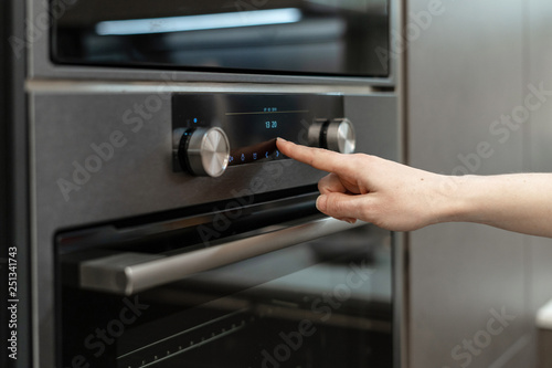 Woman hand choose program on electronic control panel built-in oven