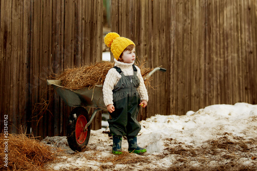 Small boy in yellow hat on the farm against the hay photo