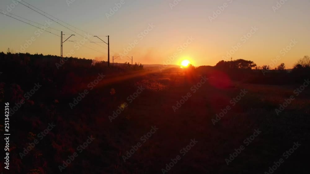 Slowly flying up the drone near the railway tracks during golden hour. Day is drawing to a close. Amazing sunbeams, sunset over horizon. Puff of smokes coming out of the chimney from allotments. Slowly flying up the drone near the railway tracks during golden hour. Day is drawing to a close. Amazing sunbeams, sunset over horizon. Puff of smokes coming out of the chimney from allotments.