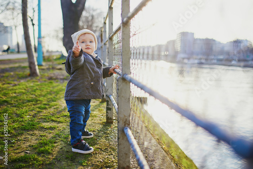 One year old girl standing next to metal fence in park © Ekaterina Pokrovsky