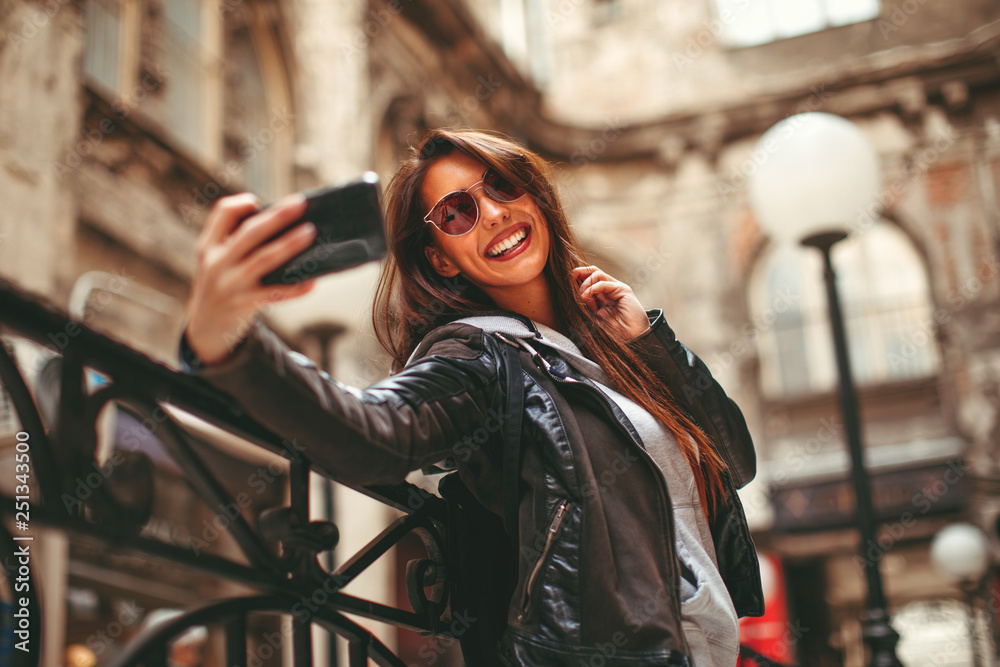 Fototapeta premium Young happy woman taking selfie on the street in the city