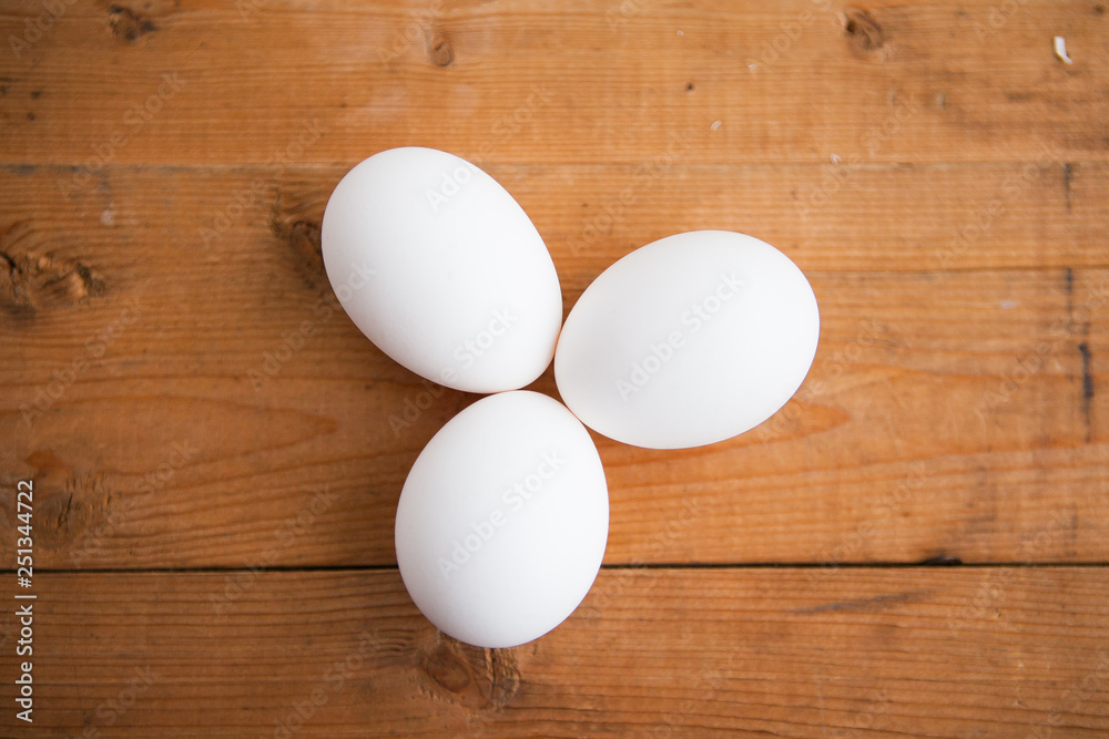 Three white eggs on a wood ground