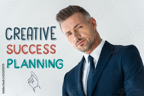 low angle view of handsome businessman looking at camera isolated on white with creative success planning