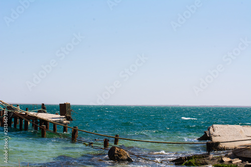 destroyed pier at the black sea coast spit Belyaus in the summer bright warm day photo