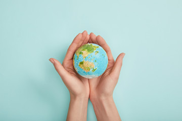 top view of woman holding planet model on turquoise background, earth day concept
