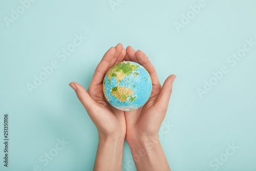 top view of woman holding planet model on turquoise background, earth day concept