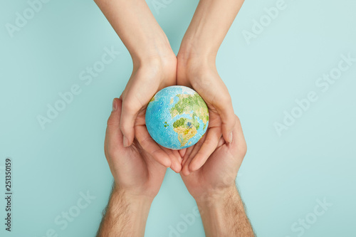 Fototapeta Naklejka Na Ścianę i Meble -  top view of man and woman holding planet model on turquoise background, earth day concept