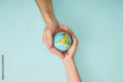 Fototapeta Naklejka Na Ścianę i Meble -  top view of man and woman holding planet model on turquoise background, earth day concept