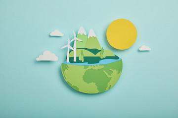 Top view of paper cut planet with renewable energy sources on turquoise background, earth day concept