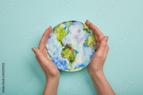 Fototapeta Naklejka Na Ścianę i Meble -  top view of woman holding planet picture on turquoise background, earth day concept