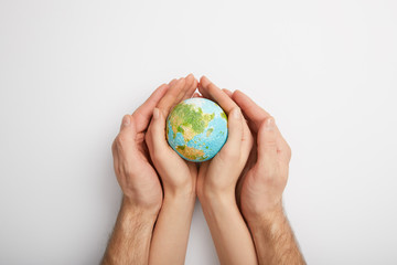 top view of man and woman holding planet model on grey background, earth day concept