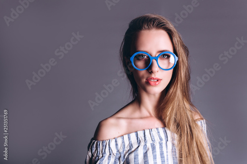 Close up portrait of young gorgeous beauty student girl in srtiped shirt and in fashionable eyeglasses on grey background looking at camera photo