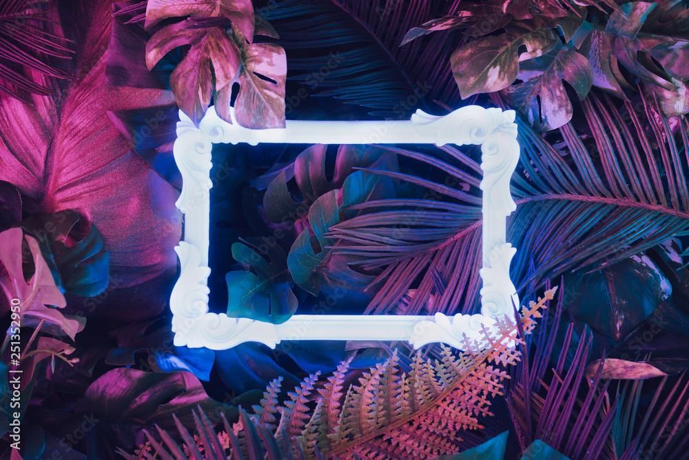 Creative fluorescent color layout made of tropical leaves with neon light vintage frame. Flat lay. Nature concept. - obrazy, fototapety, plakaty 