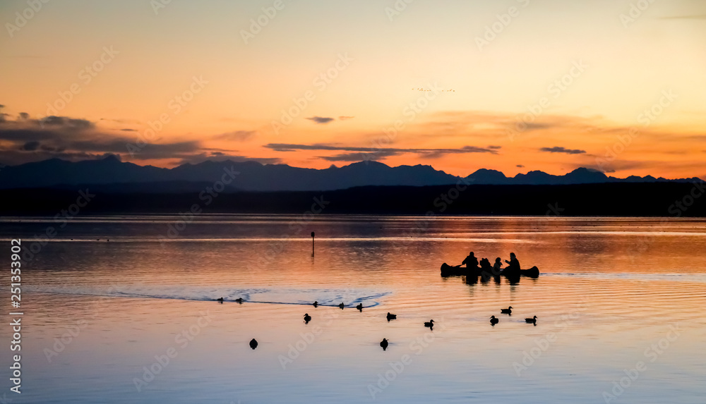 family in kayak at orange sunset, dark silhouette in the lake 