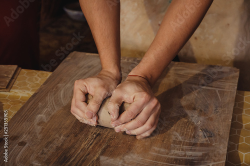 Close-up man hands mixing clay ball before working on a pottery wheel
