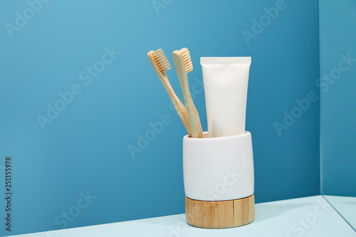 Εκτύπωση καμβά holder with bamboo toothbrushes, toothpaste in tube and mirror on table and blue