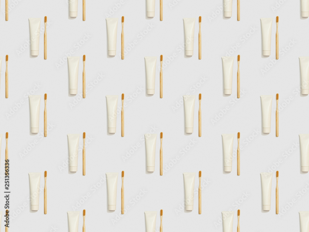 vertically located bamboo toothbrushes and toothpaste in tubes on grey background, seamless background pattern vertically located bamboo toothbrushes and toothpaste in tubes on grey background, seamless background pattern