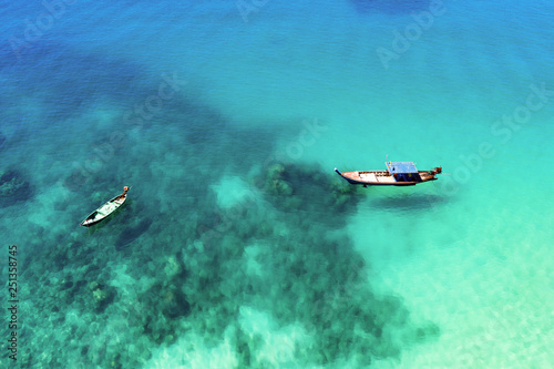 View from above, stunning aerial view of two traditional longtail boats floating on a turquoise and clear sea. Tropical beach with white sand, Freedom beach, Phuket, Thailand.