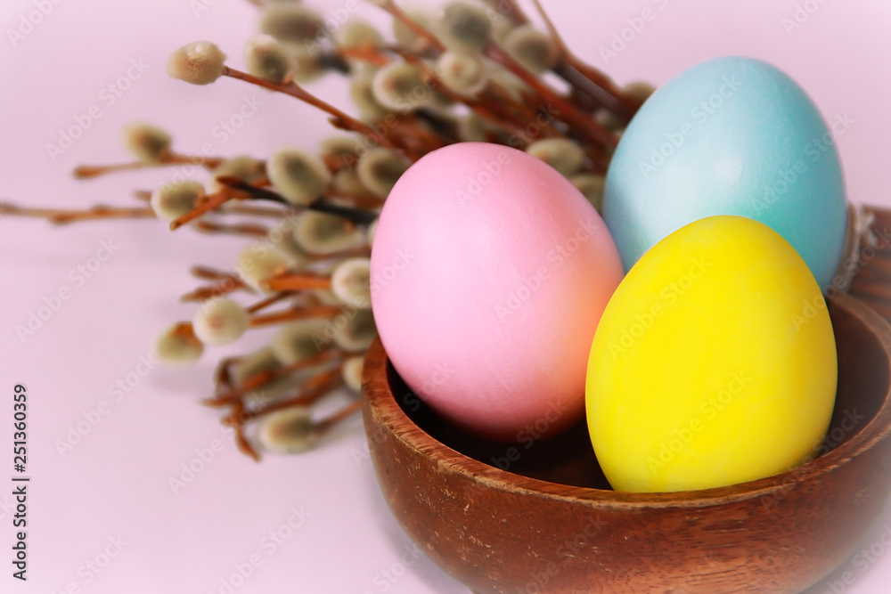Naklejka premium pink yellow blue eggs against a background of willow and flowers for the Easter holiday