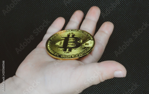Big golden souvenir coin Bitcoin digital currency in the hands of a child