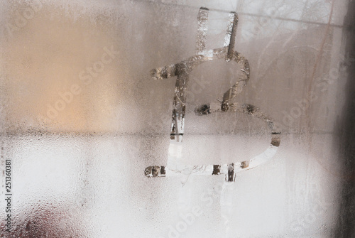 Bitcoin symbol on the misted glass of a wooden old window