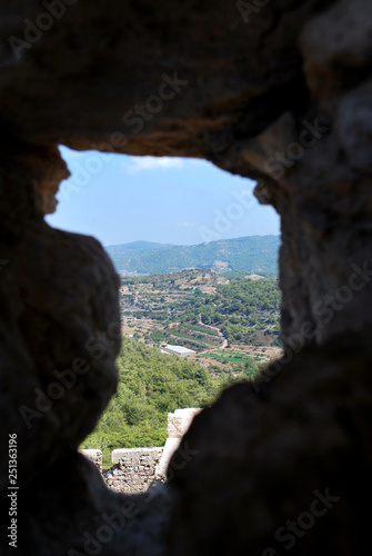 View of the hills of the island through the loophole in the stone wall of the ruins of the castle Kritinia  Village Kritinia  the island of Rhodes  Greece