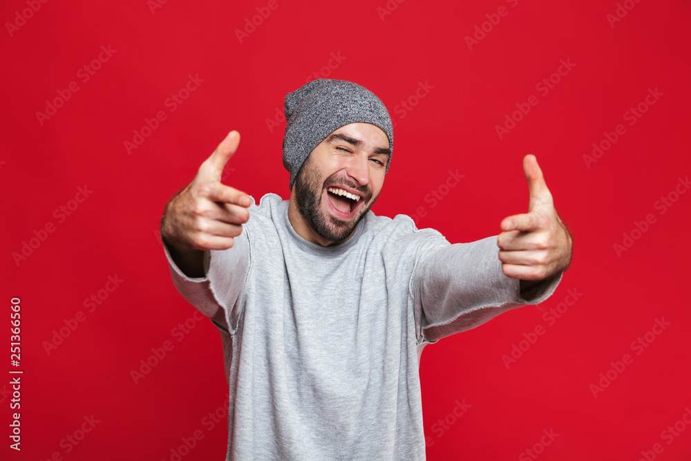 Image of smiling man 30s with beard and mustache pointing fingers at you while standing, isolated over red background Image of smiling man 30s with beard and mustache pointing fingers at you while standing, isolated over red background
