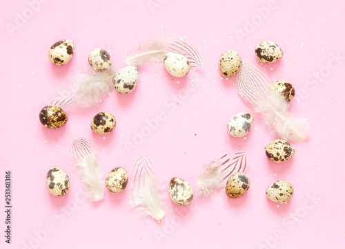  Frame with quail eggs, feathers and and golden glitter on pink background.