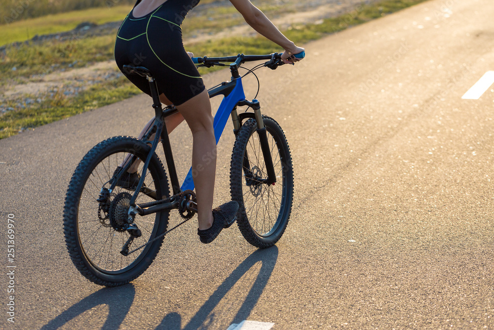 A girl riding a mountain bike on an asphalt road, beautiful portrait of a cyclist at sunset A girl riding a mountain bike on an asphalt road, beautiful portrait of a cyclist at sunset