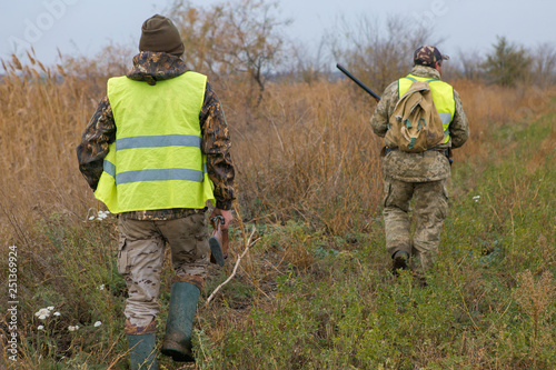 Hunter with a gun and a dog go on the first snow in the steppe, Hunting pheasant in a reflective vest 