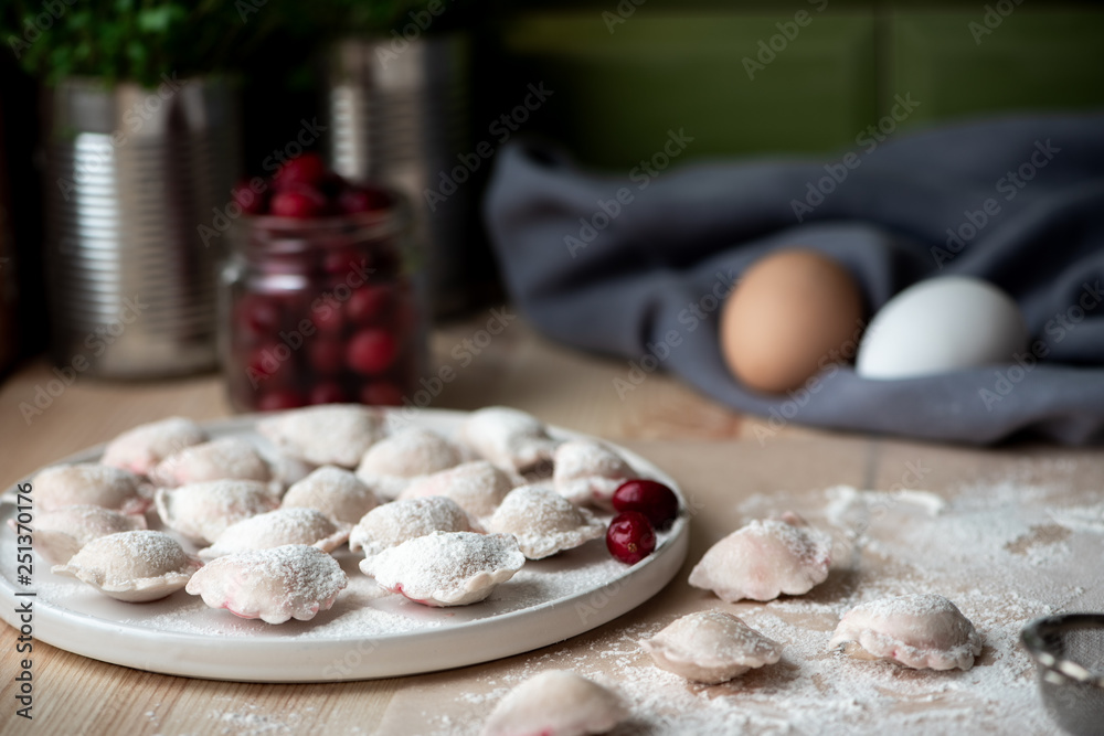 Fototapeta premium Uncooked dumplings with berry on the kitchen table.