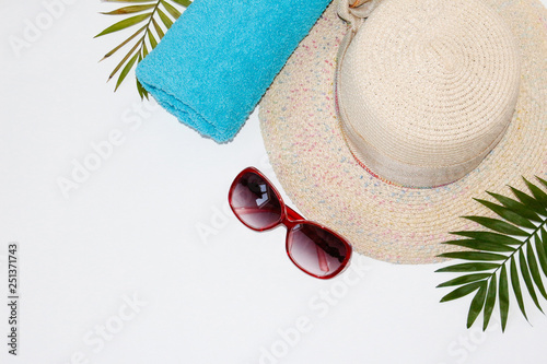 Flat lay summer beach holiday accesorries on white background with palm leaf, camera, straw hatand and sunglasses.Space for text. Travel and beach vacation, top view.Overhead view of woman's swimwear. photo