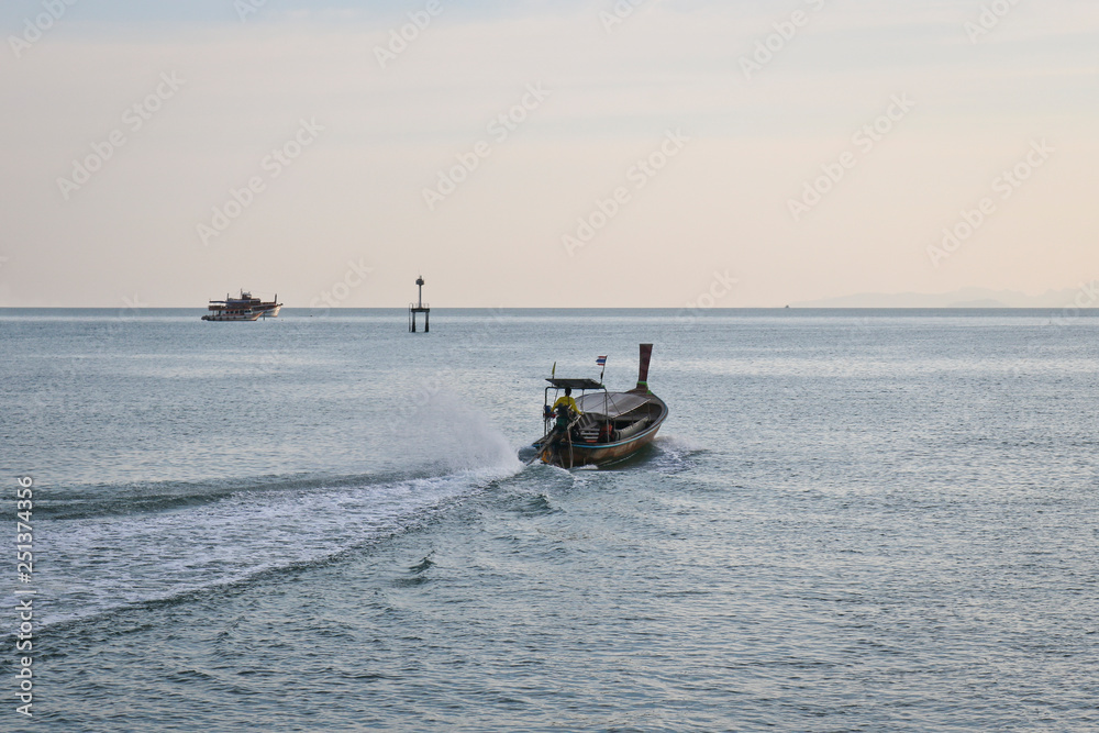 An empty long-tailed motor boat floats on the sea in the evening - end of working day, Thailand.