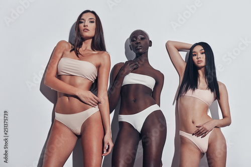 Real beauty. Three attractive mixed race women looking at camera while standing against grey background photo