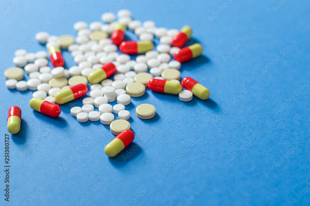 Heap of various pills isolated on blue background.