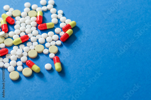 Heap of various pills isolated on blue background.