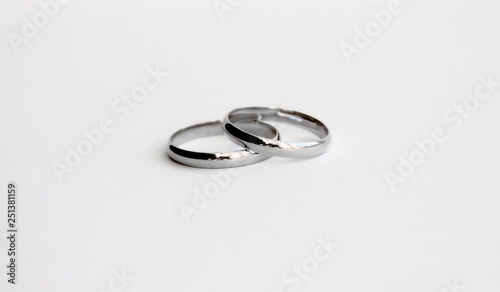 Two silver wedding rings are near and on a white background.