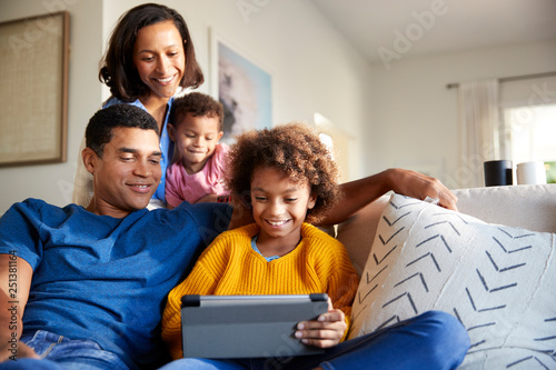 Young family spending time together using a tablet computer in their living room  front view