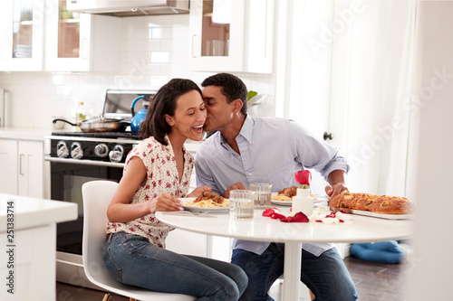 Young couple having romantic meal sitting at table in the kitchen, selective focus