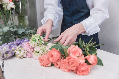 Small business. Male florist in flower shop. Floral design studio, making decorations and arrangements. Flowers delivery, creating order. The man in female profession. Gender equality concept