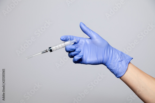 Closeup doctor's hand in rubber purple glove holding transparent syringe with closed cap. Isolated on white background. Concept rejection of vaccinations, vaccination, rabies injection