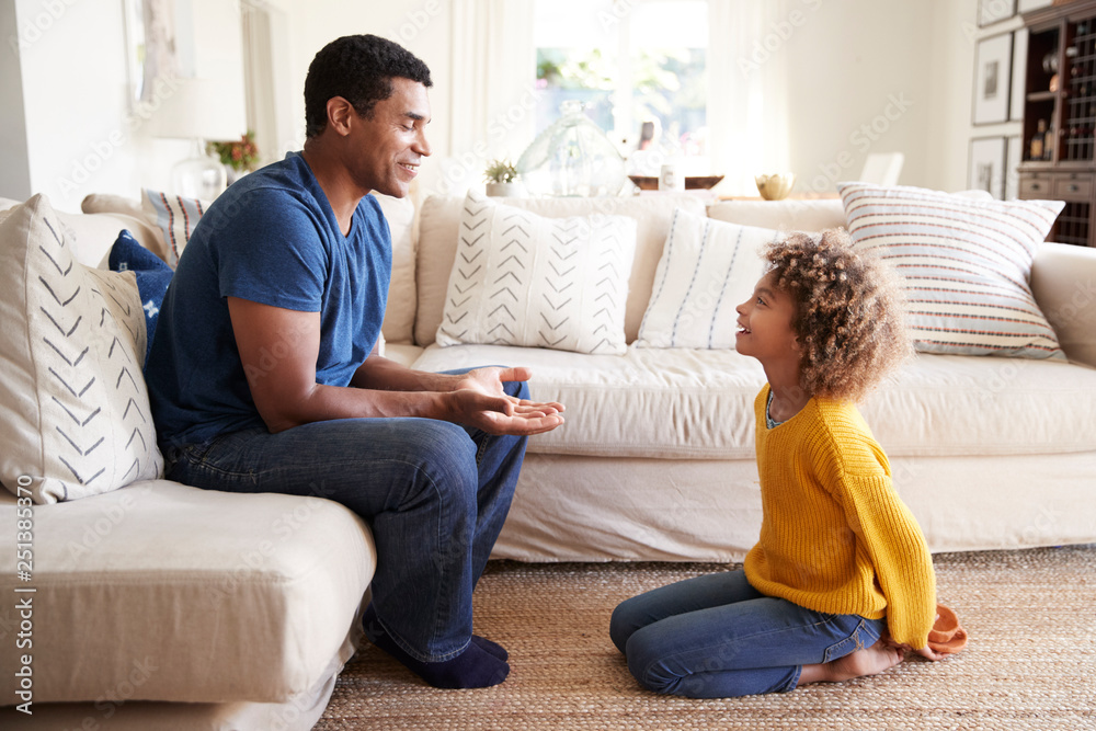 Pre-teen girl kneeling in front of her dad to give him a present she has made, close up, side view