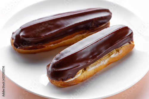 Traditional french dessert. Delicious eclairs with custard and chocolate icing for sweet tooth on a plate. Pastry products.