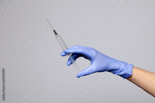 Closeup doctor's hand in rubber latex purple glove hold transparent syringe. Isolated on white background. Concept rejection of vaccinations, injection HIV, epidemic of AIDS, prevention hepatitis