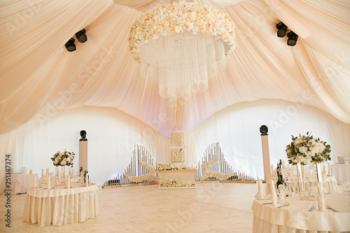Wedding ceremony in a beautiful tent decorated with bouquets of flowers and white cloth