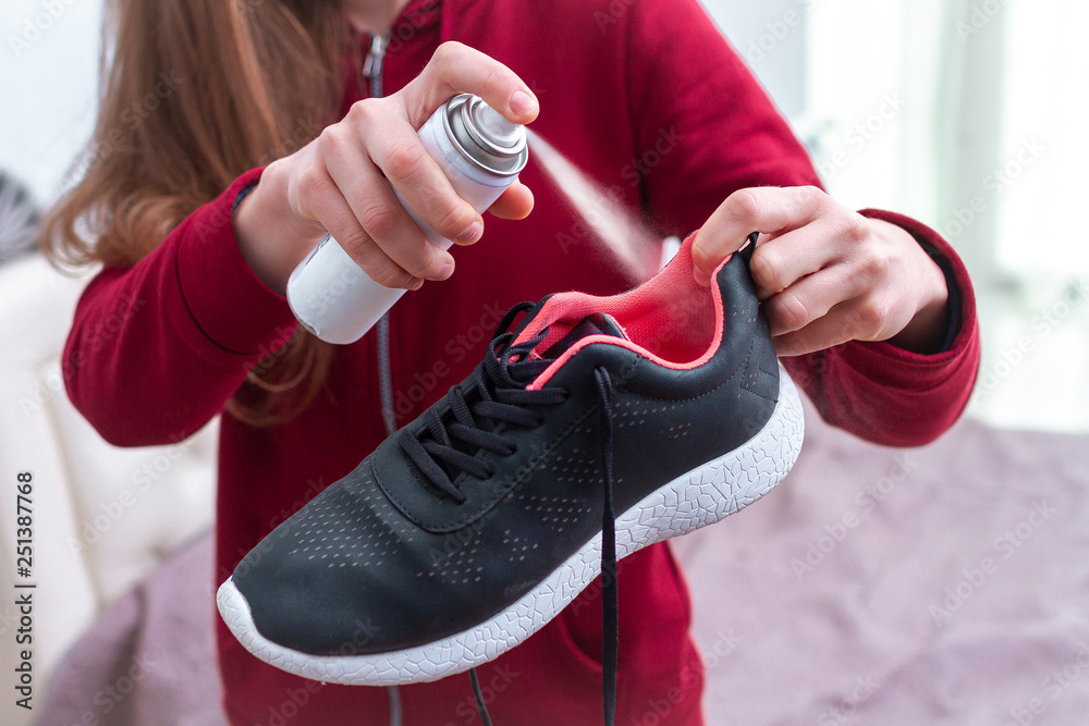 A young woman spraying deodorant on sweaty running shoes for eliminate  unpleasant, bad smell. Shoe shine and care. Sport footwear needs in  cleaning and odor removal. Stock Photo | Adobe Stock