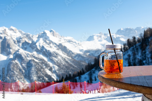 Mug aperol stands on the table of a street cafe against the backdrop of the mountains.